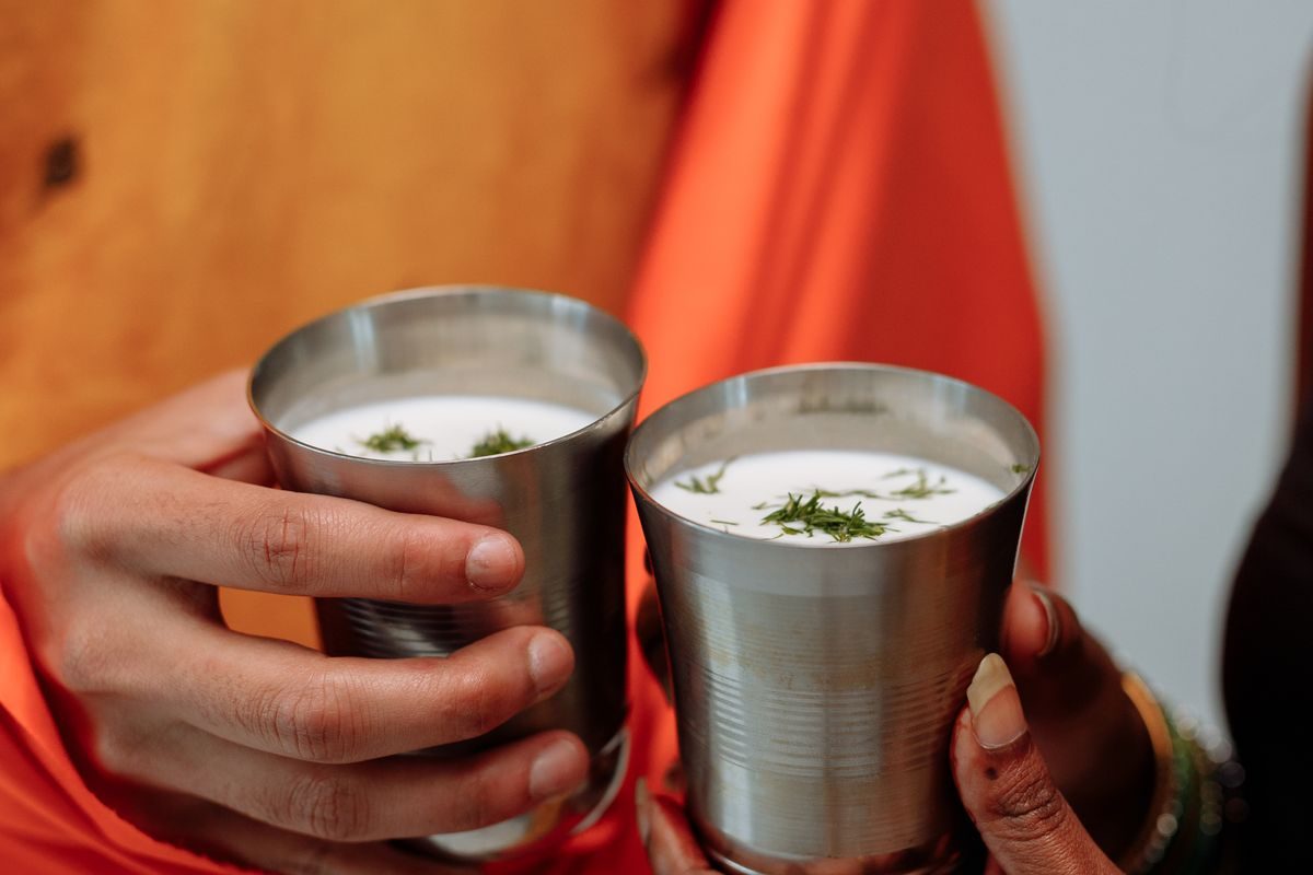 Two steel glasses of fresh buttermilk (chaas) garnished with coriander, an Ayurvedic drink for digestion